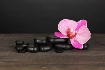 Fototapeta na wymiar Kamienie spa z orchid kwiat na drewnianych tabeli na szarym