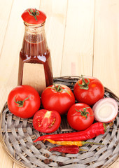 Ketchup and ripe tomatoes on wooden table