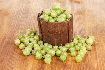Green gooseberry in wooden cup on wooden background