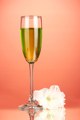 glass with cocktail and gladiolus bud on red background