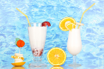 Delicious milk shake with fruit on table on blue sea background