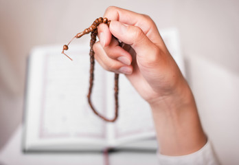 young muslim girl with rosary praying in mosque