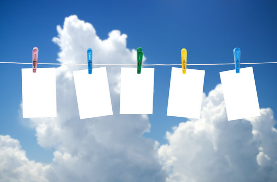 Blank photos hanging on a clothesline, blue sky on background