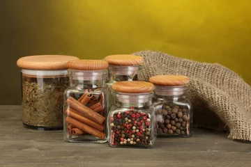 Poster jars with spices on wooden table on yellow background © Africa Studio