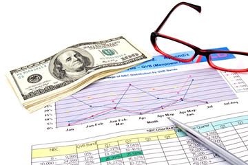 glasses,pen and dollars on financial Graphs