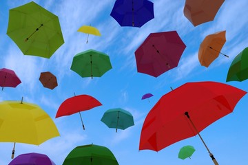 flying of multicoloured umbrellas on blue sky with clouds