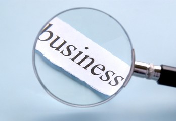 magnifying glass and the words "business" on a torn paper