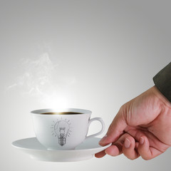 hand and a cup of coffee with light bulb drawing as concept