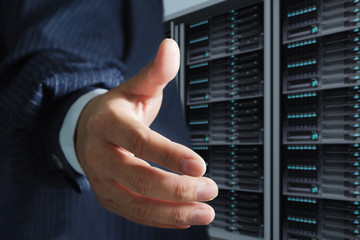 business man offers handshake in server room