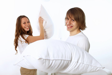 Young couple fighting with pillows