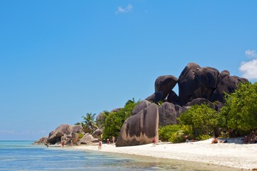 Tourists under a rock formation at Source d'Argent, La Digue