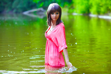 brunette woman in a red dress is wet to the waist in the water t