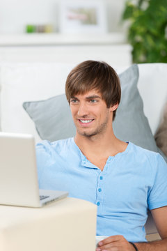 lächelnder mann mit laptop zu hause