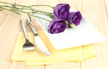 Tableware with flower on bright napkin close-up