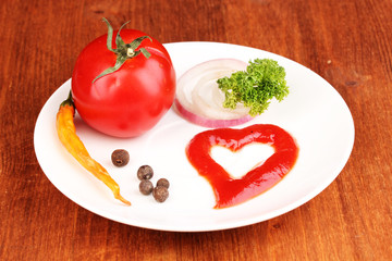 Ripe tomato and spices on plate on wooden table