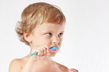 Young cute blond boy brushing his teeth