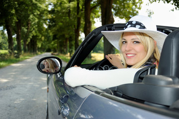 Junge blonde Frau mit Hut im Cabrio