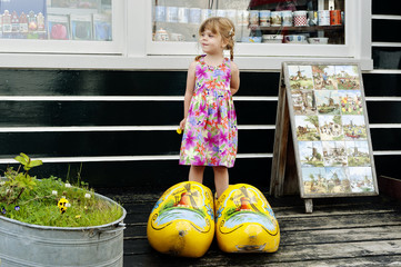 Fototapeta premium Little girl in giant wooden yellow clogs