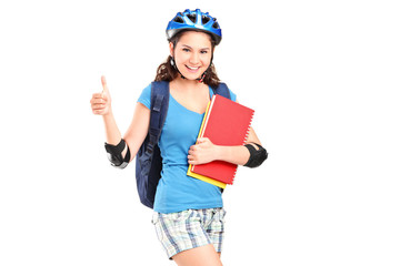 Girl on rollers holding notebooks and giving thumb up