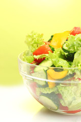 fresh vegetable salad in transparent bowl on green background