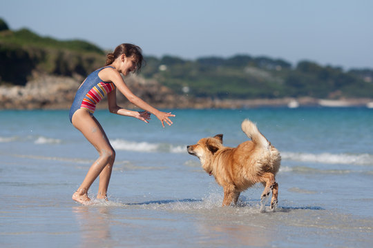 M&auml;dchen und Elowelpe spielen am Strand