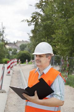 Engineer with a folder near the sidewalk repairing