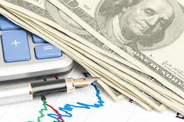 Pen,calculator and dollars on chart closeup