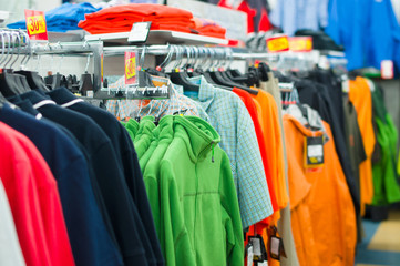 Variety of shirts, t-shirts and sweaters on stands in supermarke