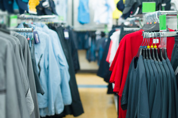 Variety of shirts, t-shirts and jackets on stands in supermarket
