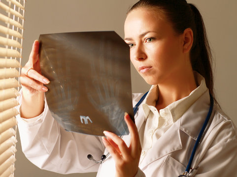 Young woman is standing near window and examining x-ray