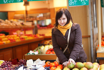 Beautiful young woman selecting fresh mangoes at market
