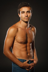 Fototapeta premium Young muscular male shirtless standing over dark background