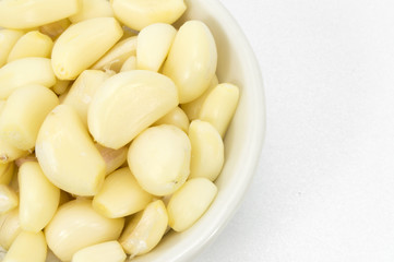 Fresh peeled garlic in a bowl, isolated on white background.