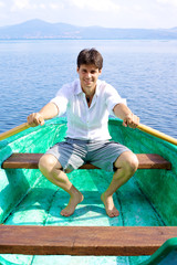 Handsome man on green wood boat rowing