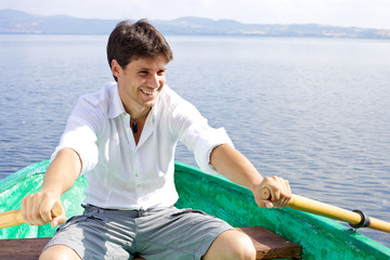 Happy handsome man rowing on a lake