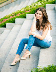 Fototapeta premium Portrait of a beautiful european woman sitting om steps