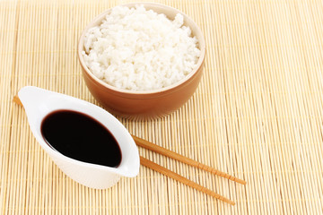 Bowl of rice and chopsticks on bamboo mat