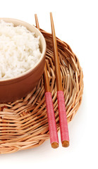Fototapeta premium Steamed white rice in brown bowl with chopsticks on woven mat, asian cuisine and healthy eating, the bowl and chopsticks rest on a round woven bamboo mat