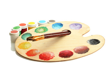 wooden art palette with paint and brushes isolated on white
