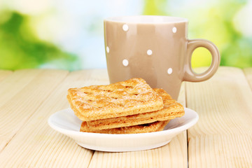 Cup of tea and cookies on wooden table on bright background