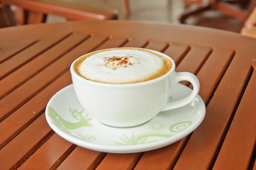 A cup of Capuchino coffee on wooden background