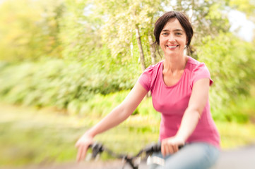 Woman riding bike on forest meadow. Lensbaby effect