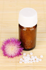 medicine bottle with tablets and flower on bamboo mat