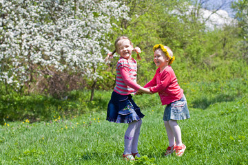 Fototapeta premium Little girls playing on a spring meadow