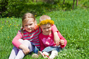 Naklejka na ściany i meble Little girls sitting in an embrace in the meadow