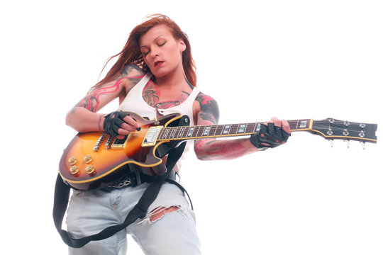 Attractive punk girl with tattoos playing electrical guitar