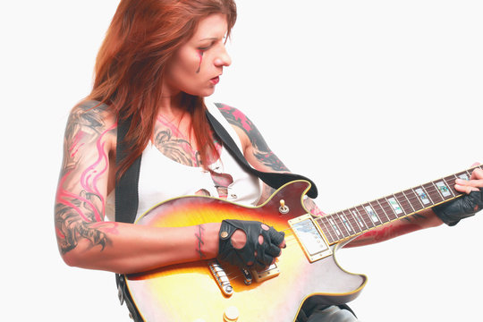 Attractive punk girl with tattoos playing electric guitar