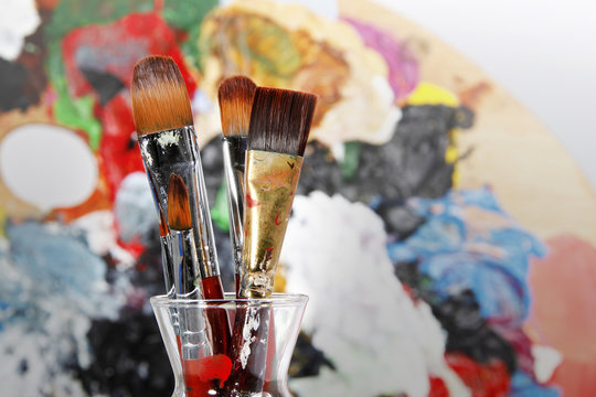 Assorted dirty old painting brushes in a glass flask.