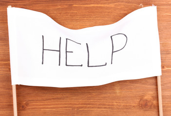 Help written on white cloth on wooden background