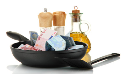 Banknotes in a frying pan with cooking spatula isolated on